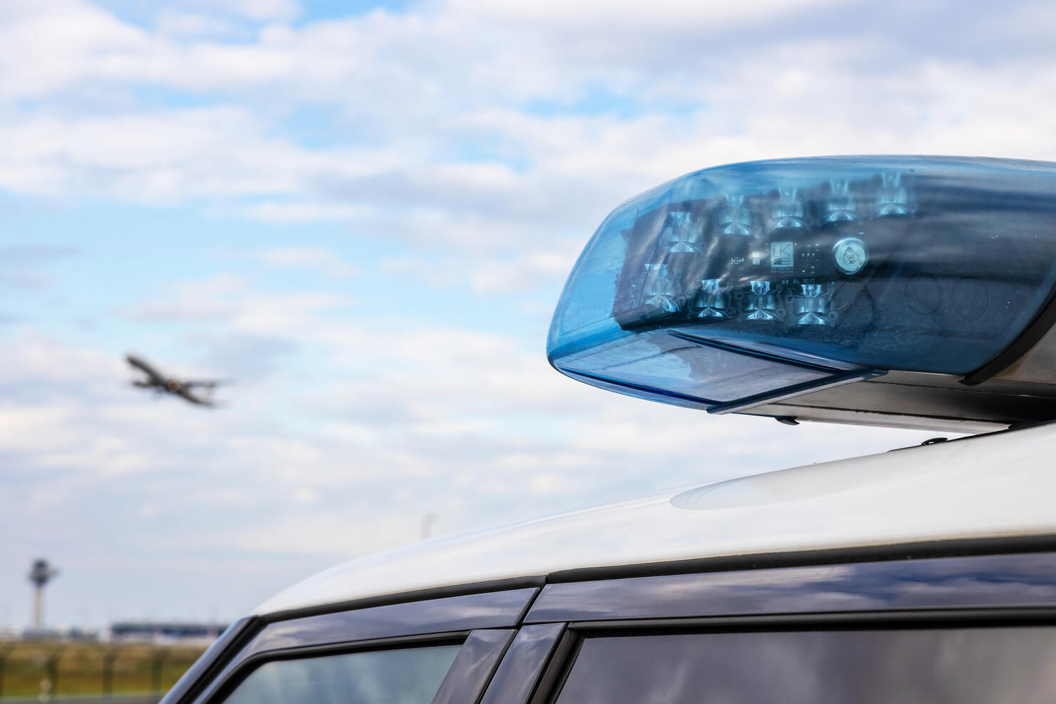 Police light on a car of the German police with passenger aircraft in the sky