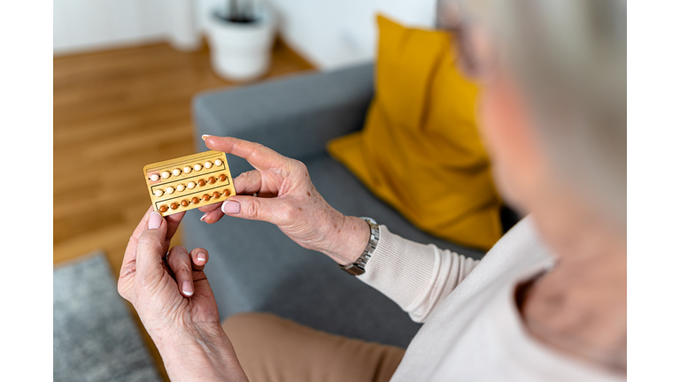 A close-up photo of a woman using pills for controlling hormones during menopause.