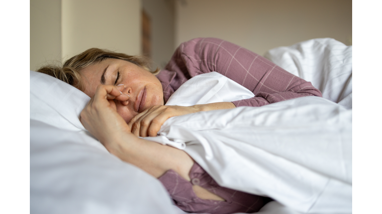 Mature woman suffering from menopause symptoms while lying in bed