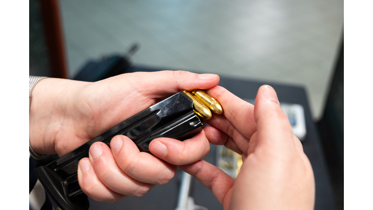 woman hands loading pistol magazine with bullets