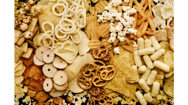 Colorful mix of salty snacks for beer varieties: chips and pretzels, onion rings and crackers.
