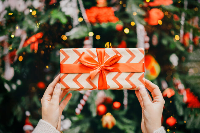 Soft woman hands putting gift box under the Christmas tree