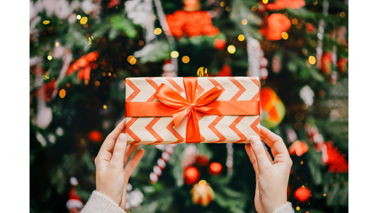 Soft woman hands putting gift box under the Christmas tree