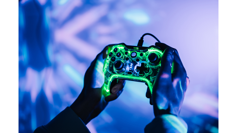 A man with a neon joystick in the dark playing video game on a computer.