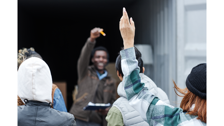 Close up of young woman raising hand at outdoor auction