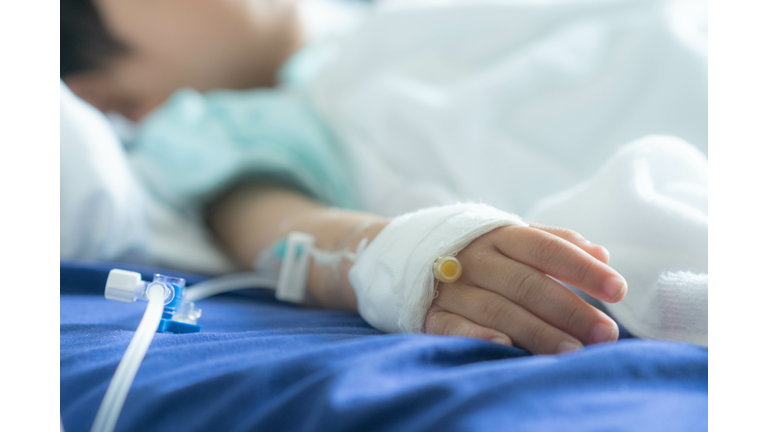 Asian todler in hospital with intravenous saline. Sick children, infected with the virus, are lying and being treated in beds in hospitals.