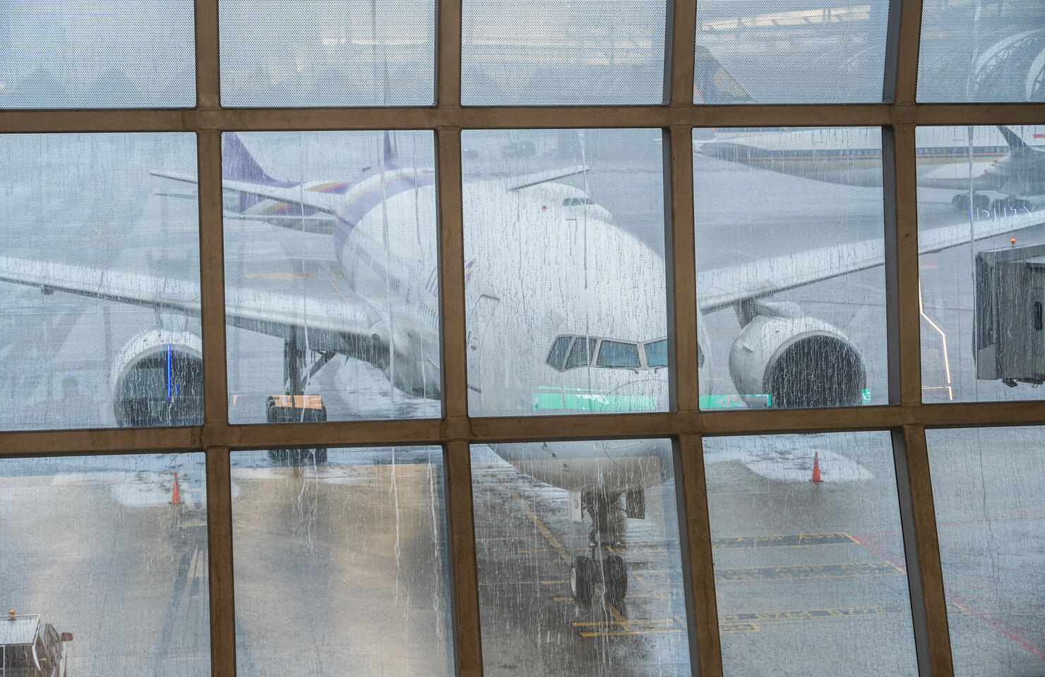 An aircraft parked at the jet bridge in airport during raining.