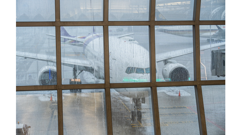 An aircraft parked at the jet bridge in airport during raining.