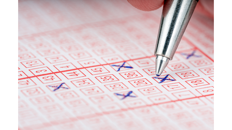 Close-up of a pen marking numbers on a lottery ticket.