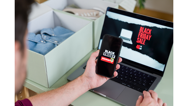 Man shopping online during black friday using laptop and smartphone