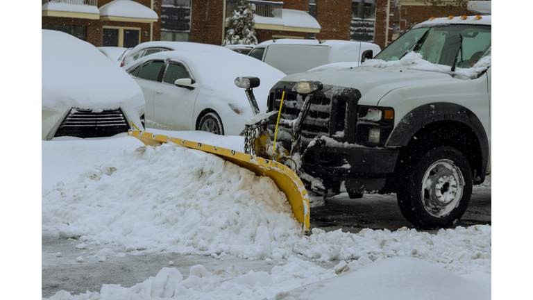 During a heavy snowfall, snowplow truck removes snow from parking lot