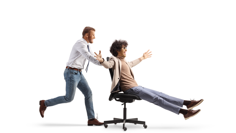 Office worker running and pushing a man on a desk chair