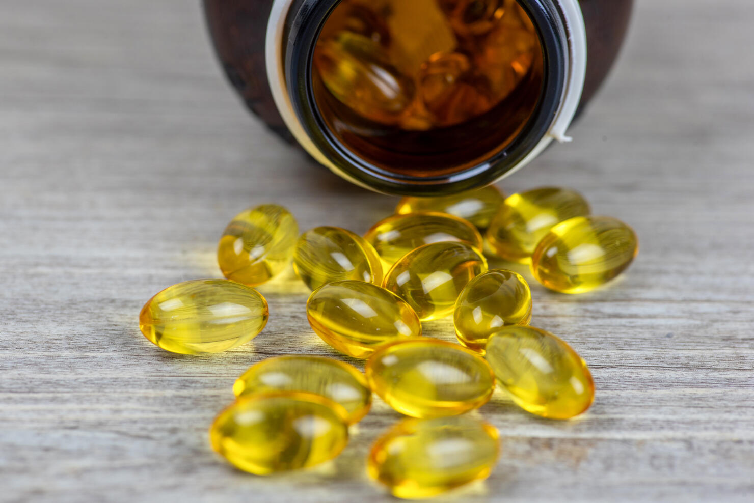 Cod liver oil omega 3 gel capsules isolated on wooden background