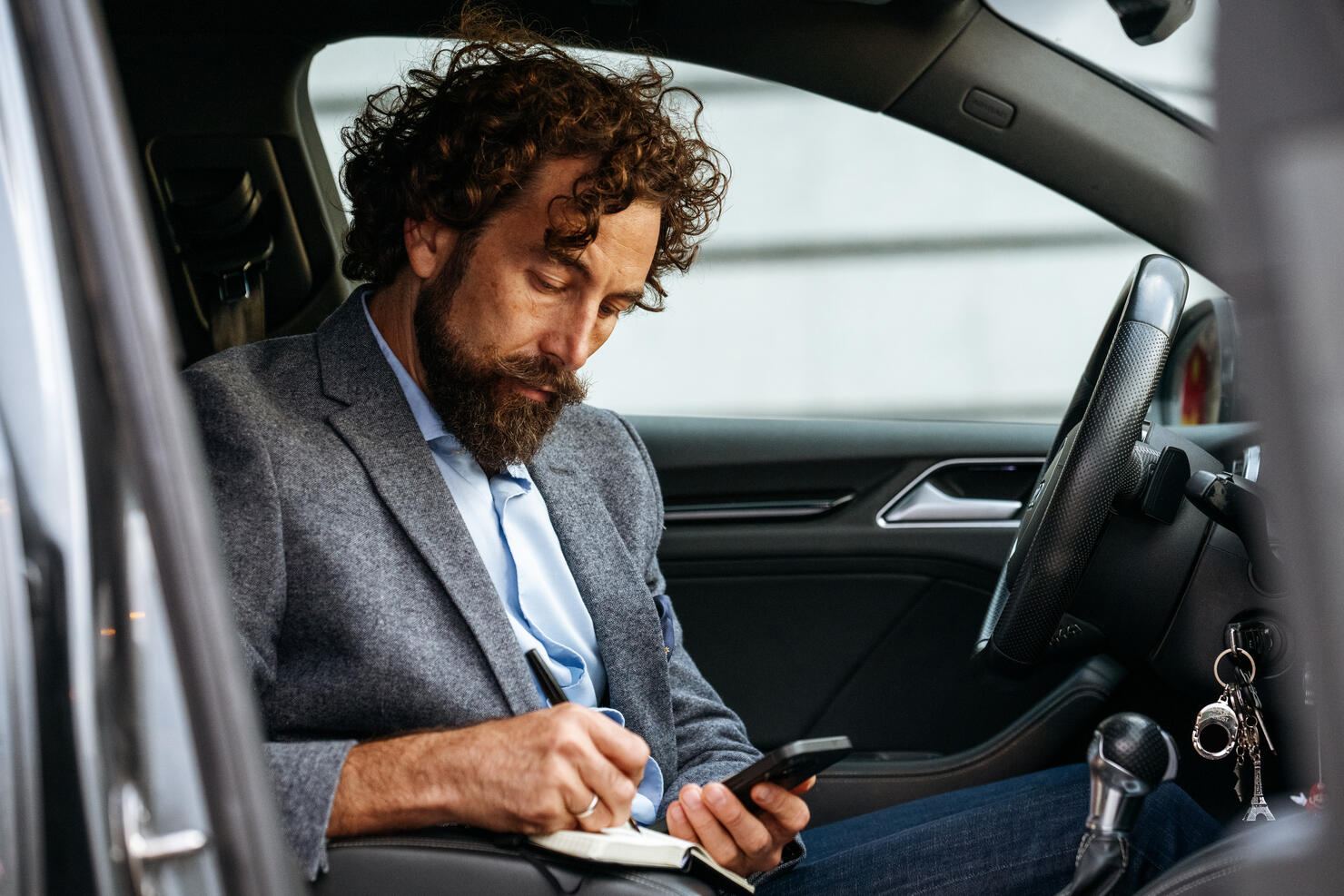 On-the-Go Productivity: Man Taking Notes in Car with Phone