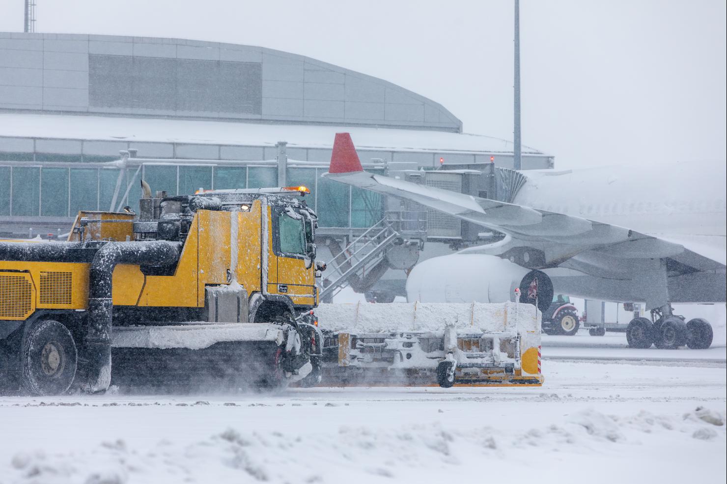 Special snow plow truck along airport runway during heavy snowfall