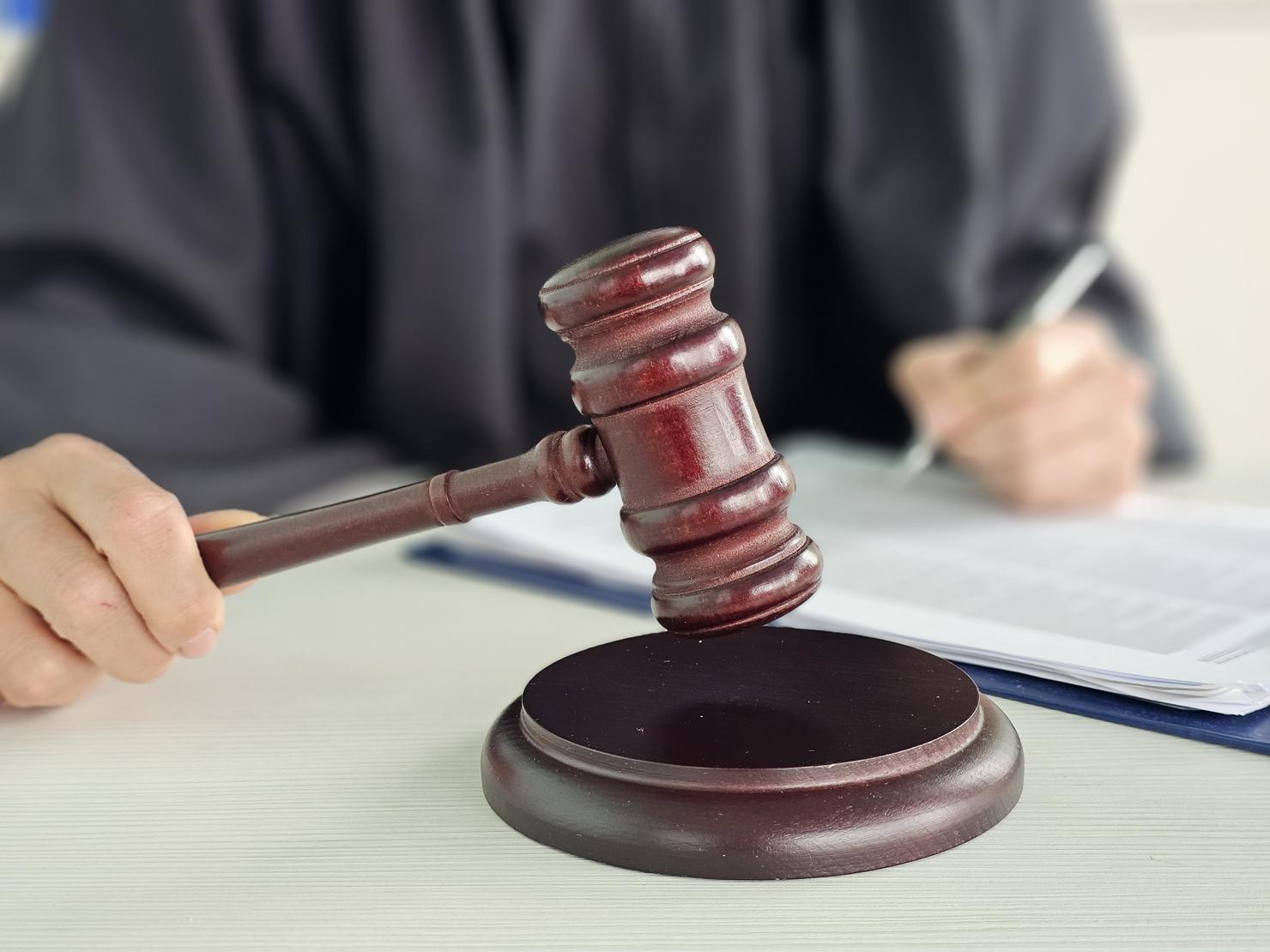 Judge presides over courtroom proceedings using gavel while reviewing case documents concept