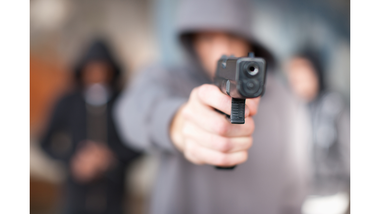 Man with gun pointed at viewer - stock photo