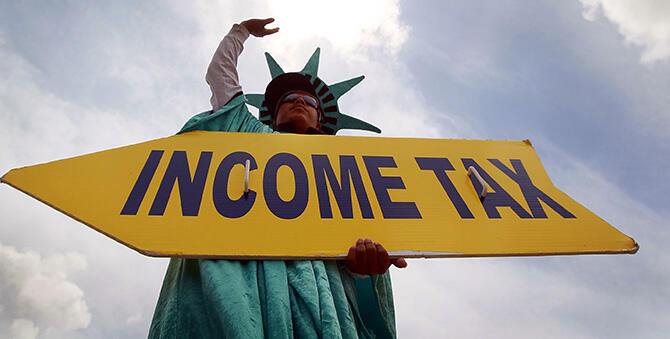 MIAMI - APRIL 14:  Felipe Castro holds a sign advertising a tax preparation office for people that still need help completing their taxes before the Internal Revenue Service deadline on April 14, 2010 in Miami, Florida.  With only one day to go before the April 15th deadline to file taxes, accountants around the U.S. are swamped with people who waited until the last day to file. (Photo by Joe Raedle/Getty Images)