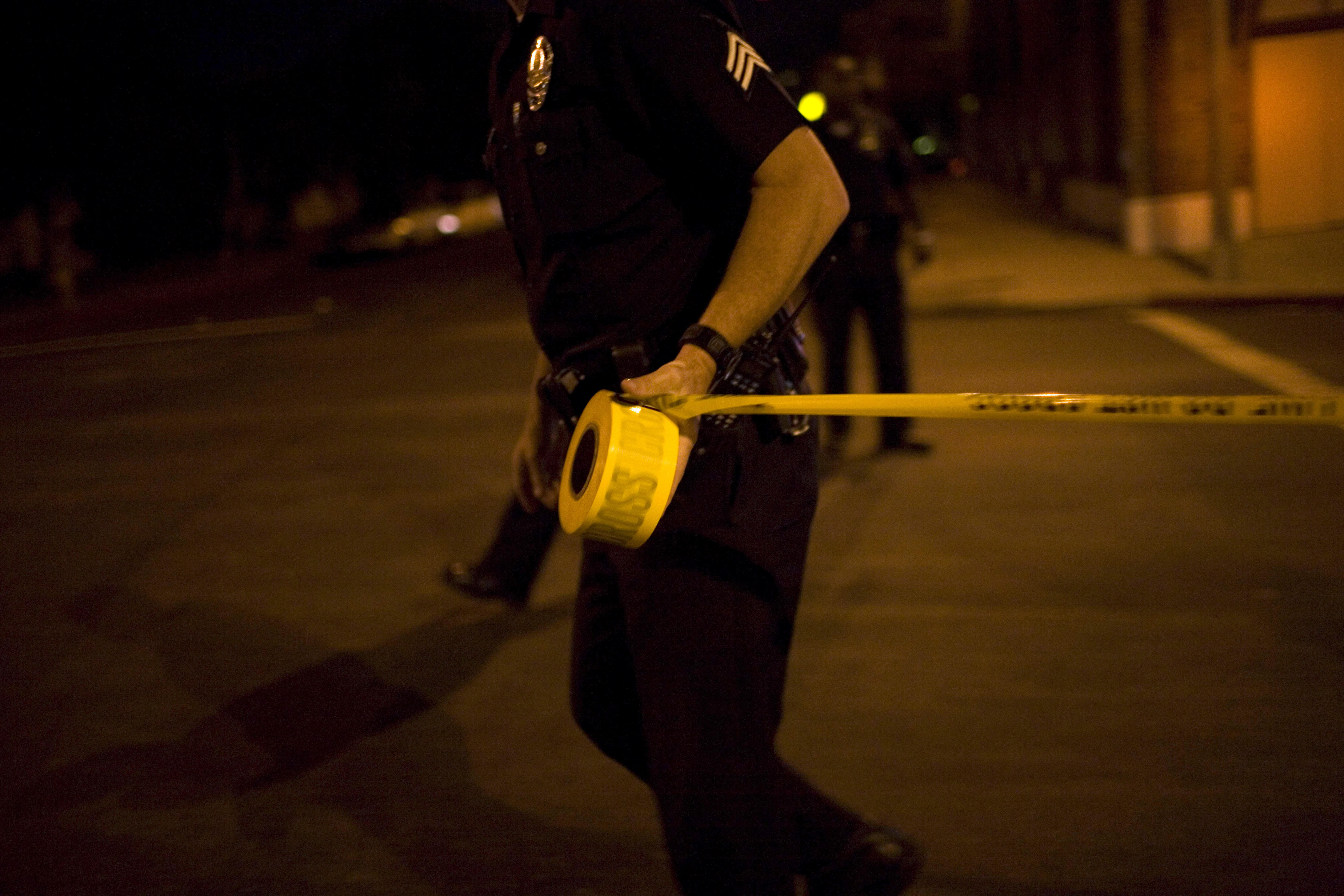 LOS ANGELES - SEPTEMBER 14: Los Angeles Police Department gang unit officers tape off a Crime Scene Investigation area following the shooting of a man September 14, 2007 in the Northeast precinct of Los Angeles, California. The injured man was taken to a 