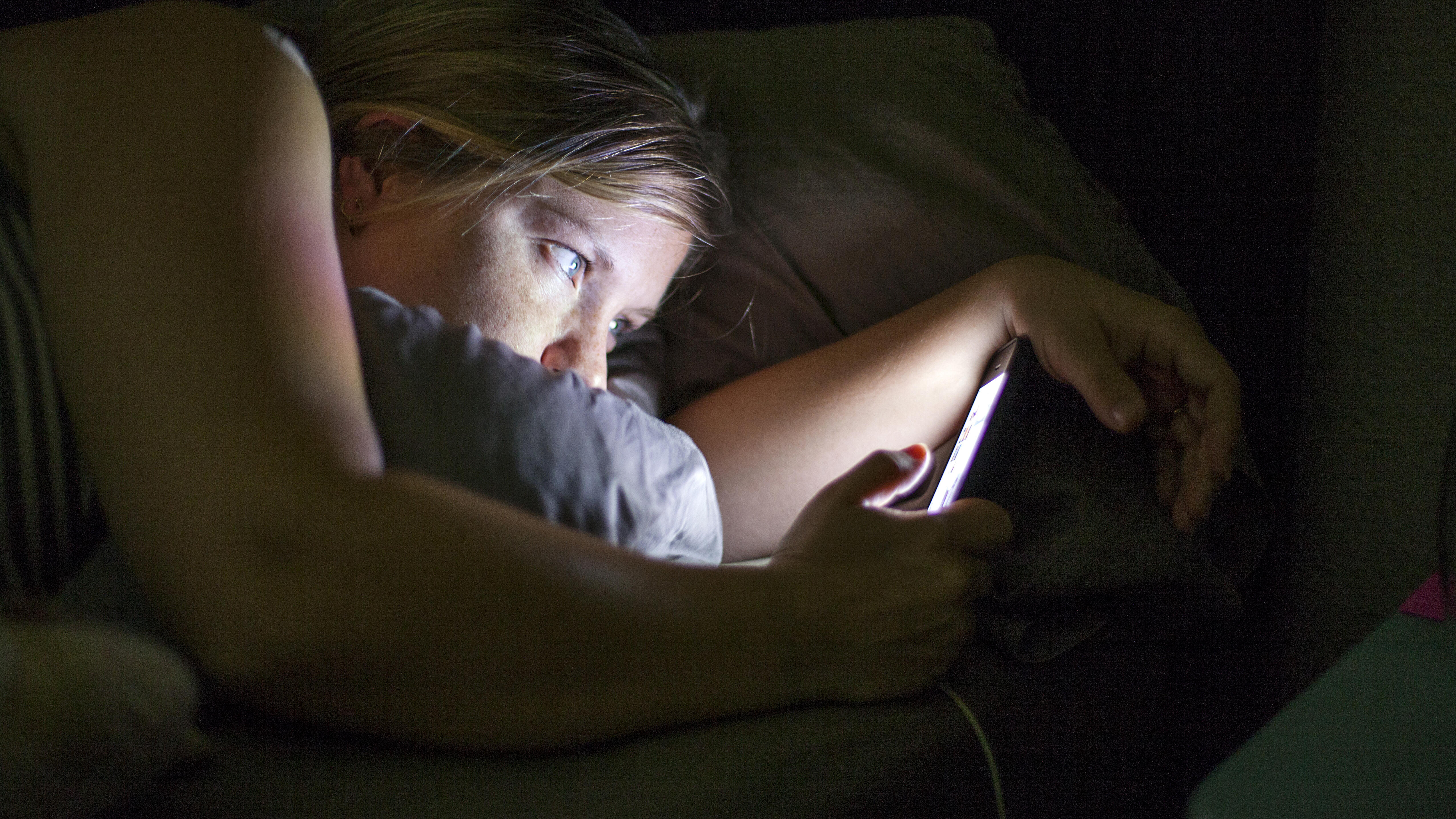 Caucasian woman using cell phone in bed