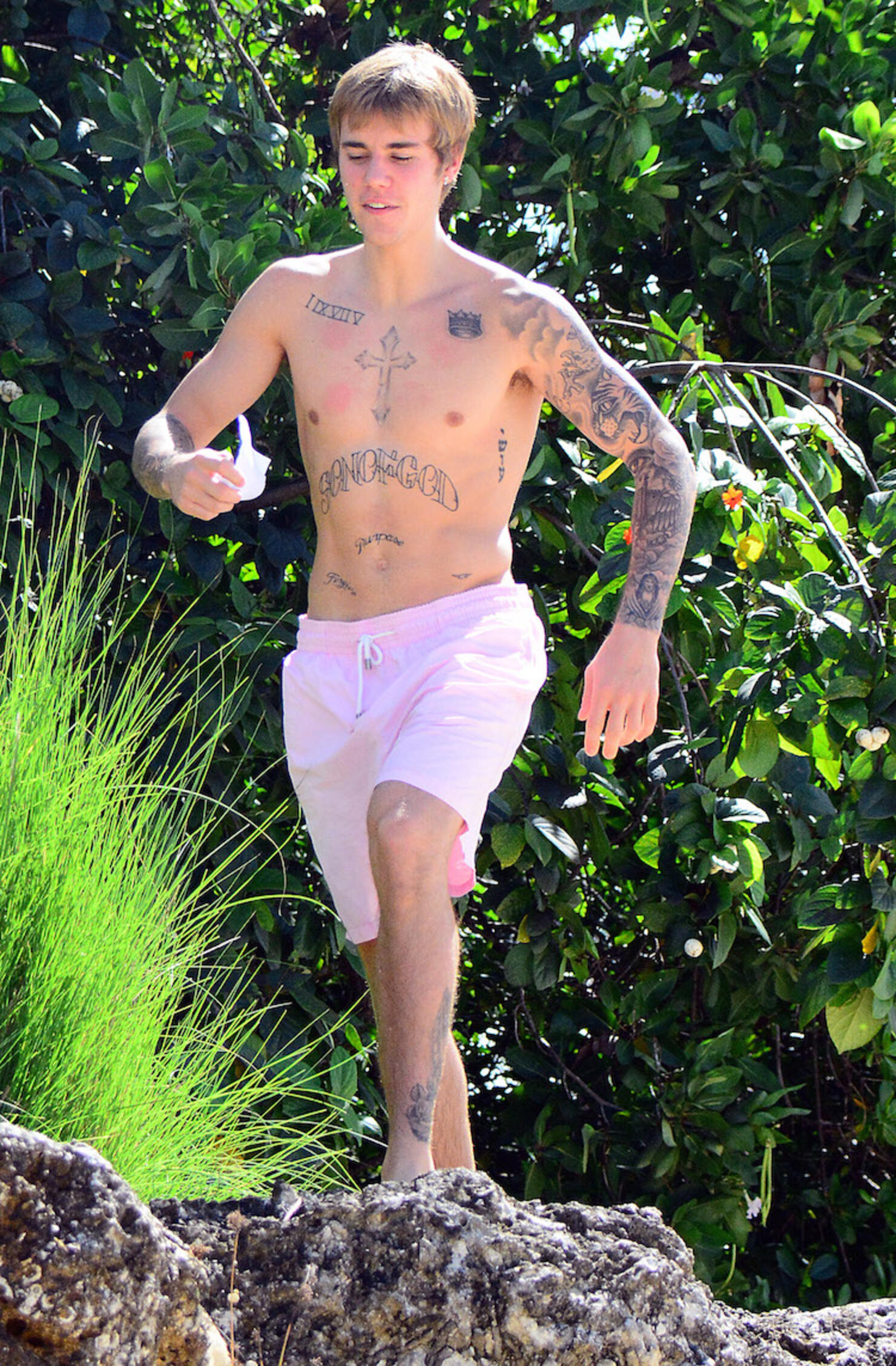 A shirtless Justin Bieber  delighted some bikini clad  with fans on the beach in Barbados.
