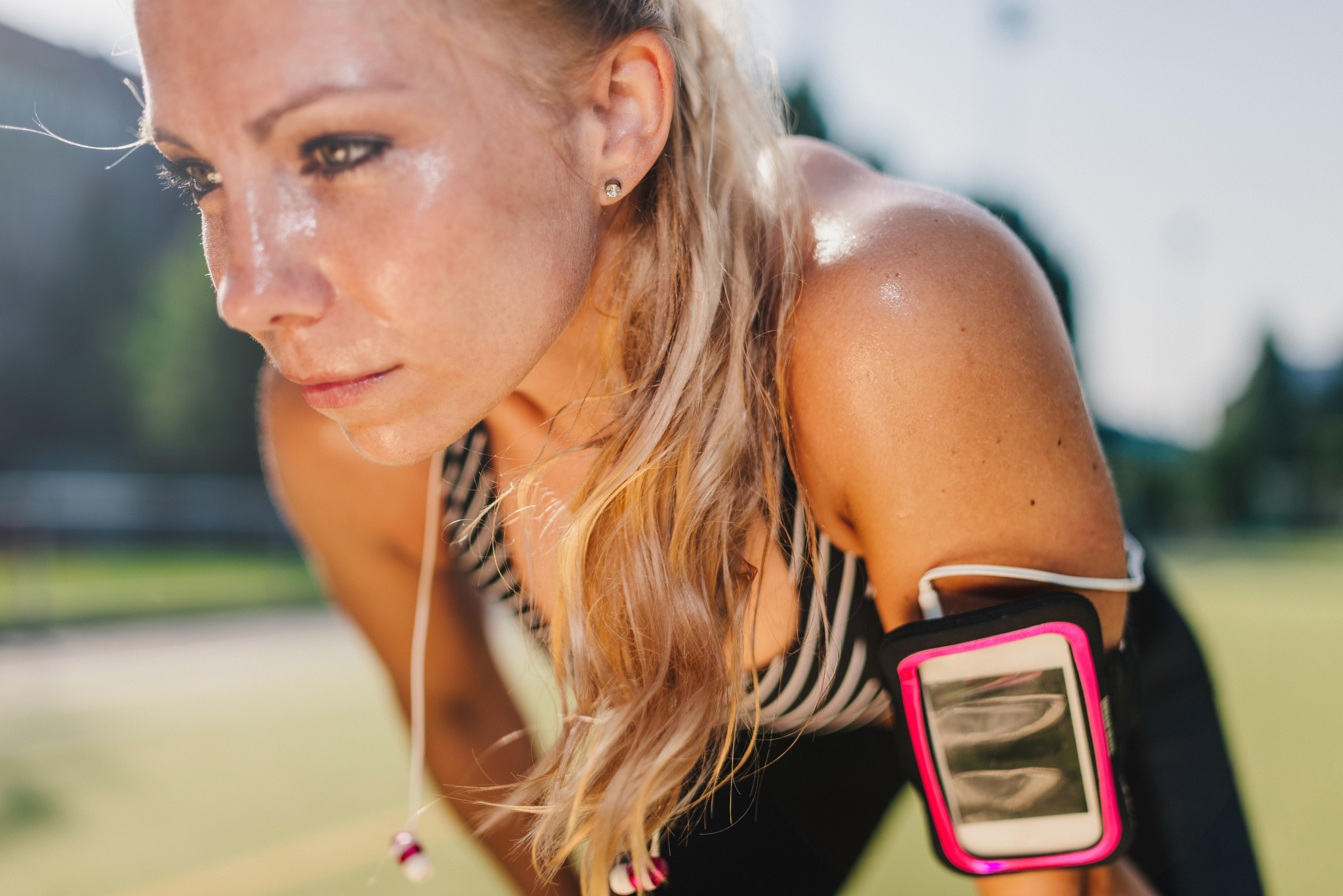 Sweaty, blond haired woman having a rest after hard workout on a sports field.