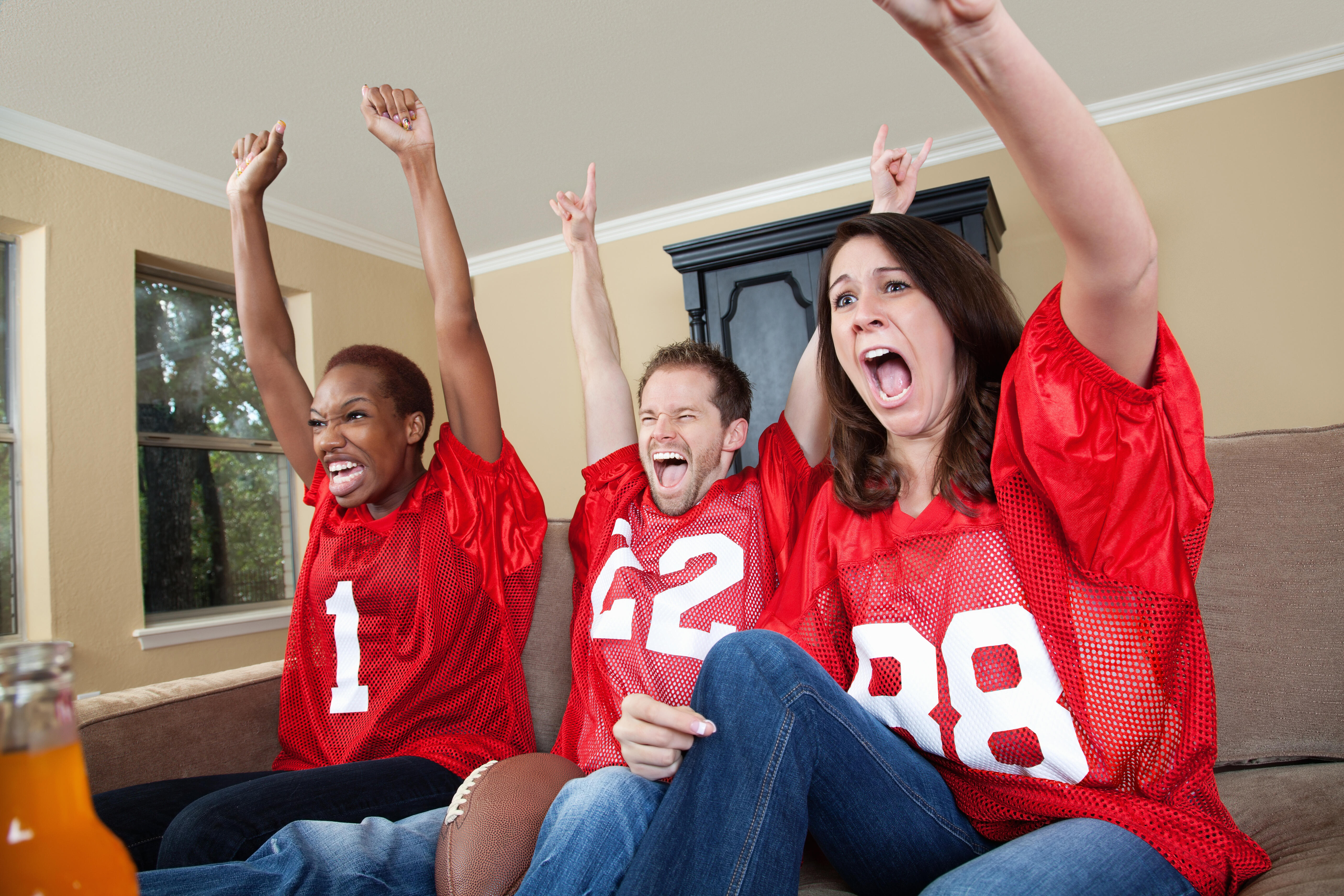 Excited sports fans cheering their football team on at home.