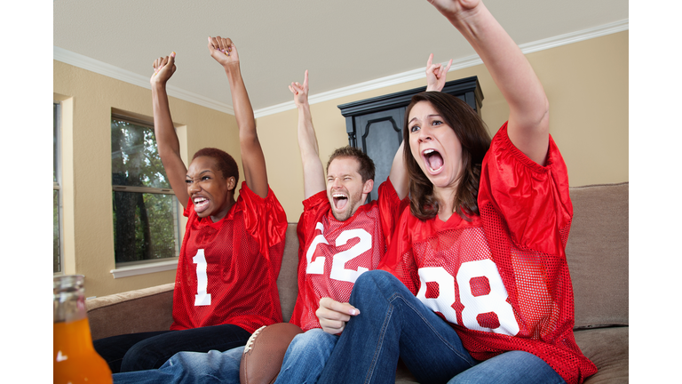 Excited sports fans cheering their football team on at home