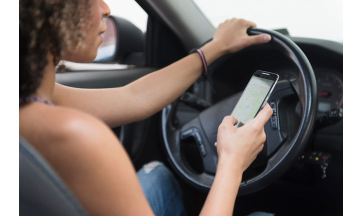 Young woman texting while driving car