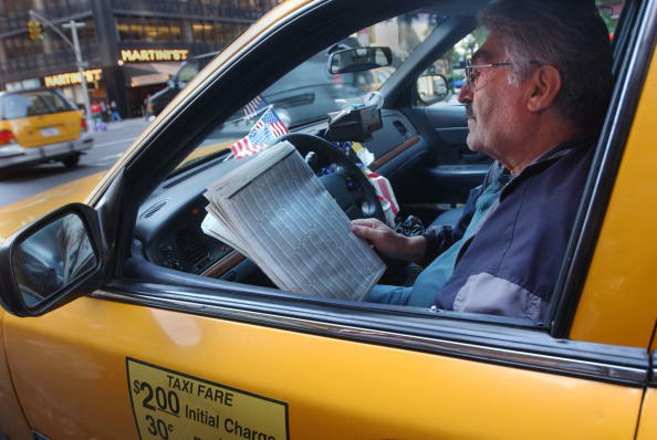 395632 01: New York City taxi driver Fayez, from Syria, reads the paper in his taxi while waiting for a passenger October 10, 2001 in New York. Taxi drivers have seen their incomes drop significantly since the terrorist attacks occurred September 11th on 