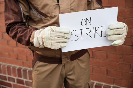 Worker Holding Placard With The Text On Strike