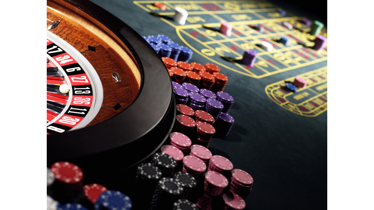 Gambling chips stacked around roulette wheel on gaming table