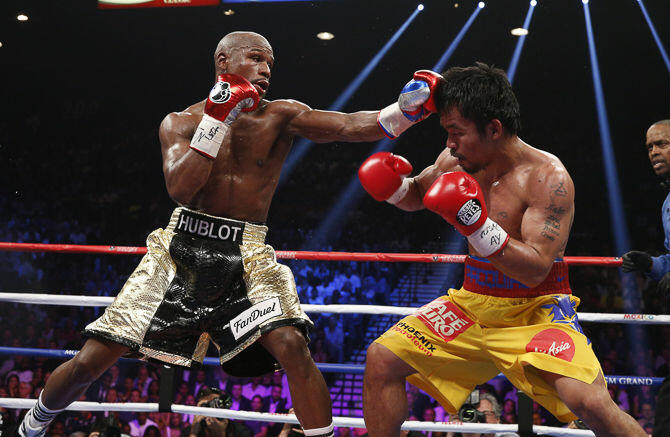 Floyd Mayweather Jr. exchange punches with Manny Pacquiao during their welterweight unification championship bout, May 2, 2015 at MGM Grand Garden Arena in Las Vegas, Nevada.  Mayweather defeated Pacquiao by unanimous decision.  AFP PHOTO / JOHN GURZINKSI