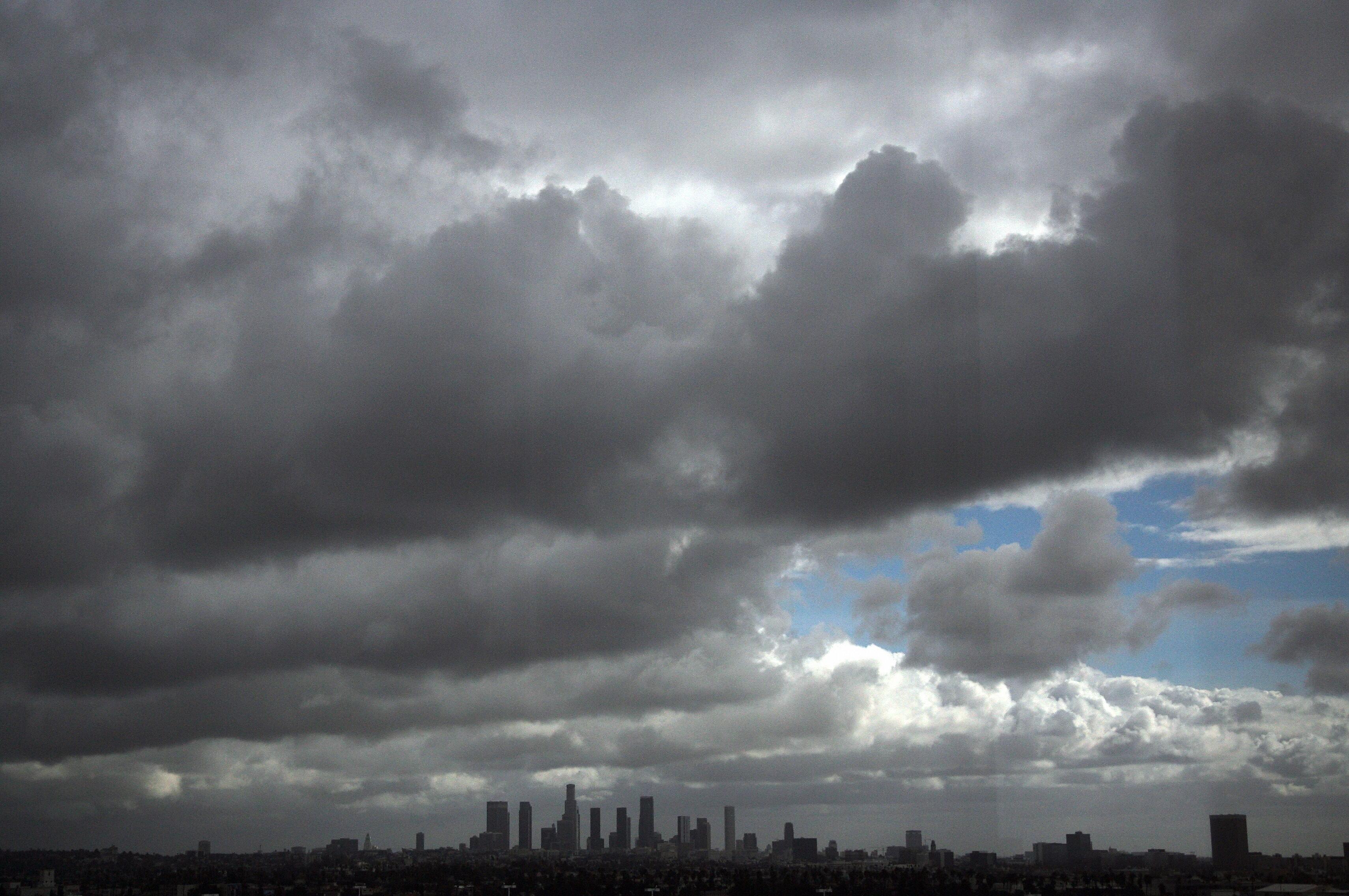 Storm clouds pass over the downtown Los Angeles skyline as the sun breaks through the thick clouds early  07 December 2007. Forecasters say urban areas can expect an inch of rain. AFP PHOTO GABRIEL BOUYS (Photo credit should read GABRIEL BOUYS/AFP/Getty I