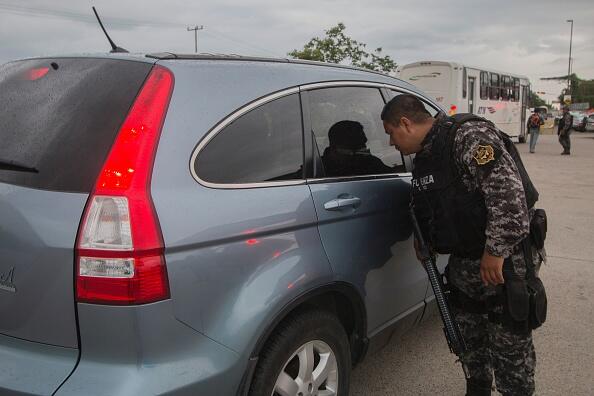 A state police officer inspects a vehicle at a checkpoint during a security operation  in Puerto Vallarta in the western Mexican state of Jalisco on August 17, 2016.  Jesus Alfredo Guzman Salazar, the son of drug lord Joaquin 
