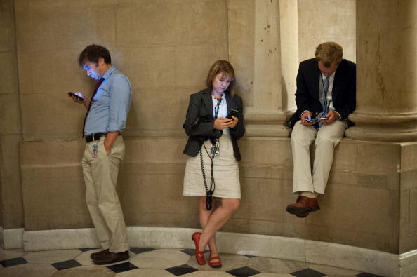 Reporters check their smartphones while waiting outside US House Speaker John Boehner's office at the US Capitol in Washington on September 30, 2013 as a possible government shutdown looms. The United States stumbled to within hours of a government shutdo