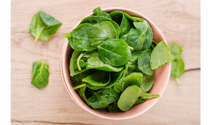 Bowl of fresh spinach leaves on wood