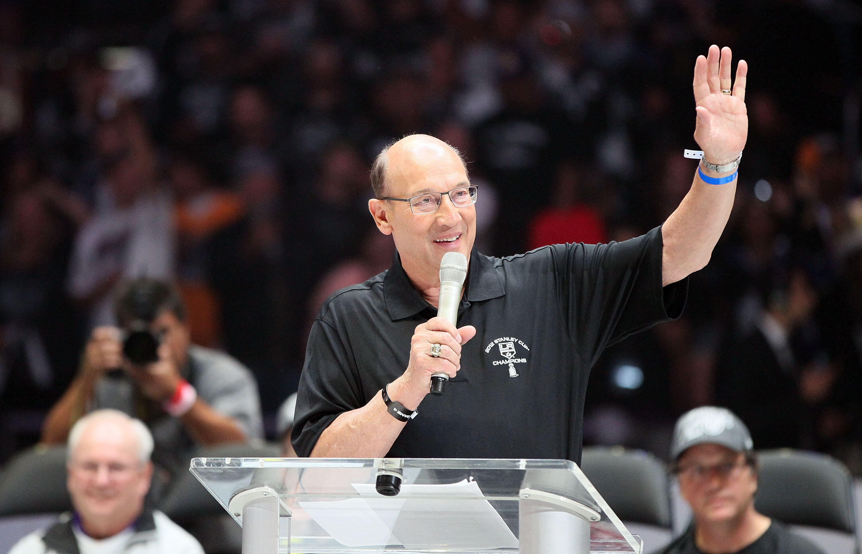 LOS ANGELES, CA - JUNE 14:  Los Angeles Kings play-by-play television announcer Bob Miller addresses the fans as General Manager Dean Lombardi (bottom right) and Assistant to the General Manager Jack Ferreira (bottom left) look on during the rally in Stap