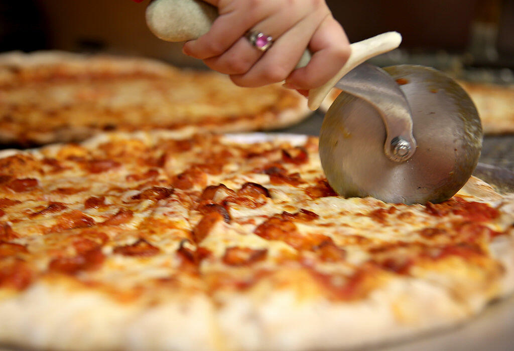 CORAL GABLES, FL - SEPTEMBER 12:  Arlet Lagoa cuts a pizza into slices at Miami's Best Pizza restaurant on September 12, 2014 in Coral Gables, Florida. Reports indicate that milk futures have risen to a record as exports by the U.S. have climbed amid shri