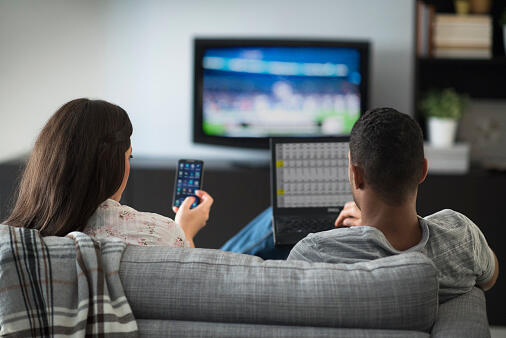 USA, New Jersey, Couple sitting in living room, using laptop and cell phone