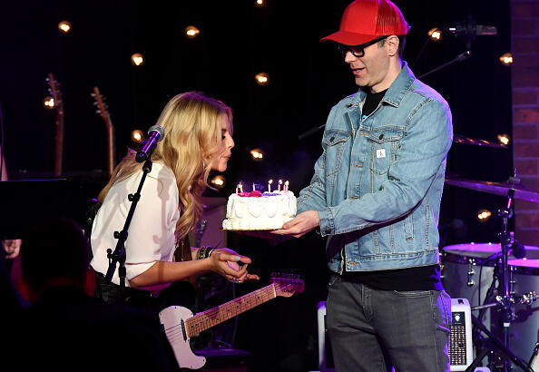 NASHVILLE, TN - MARCH 20:  Bobby Bones (R) brings Lindsay Ell a birthday cake onstage during a special Woman's March Show at Skyville Live on March 20, 2017 in Nashville, Tennessee.  (Photo by Rick Diamond/Getty Images for Skyville)