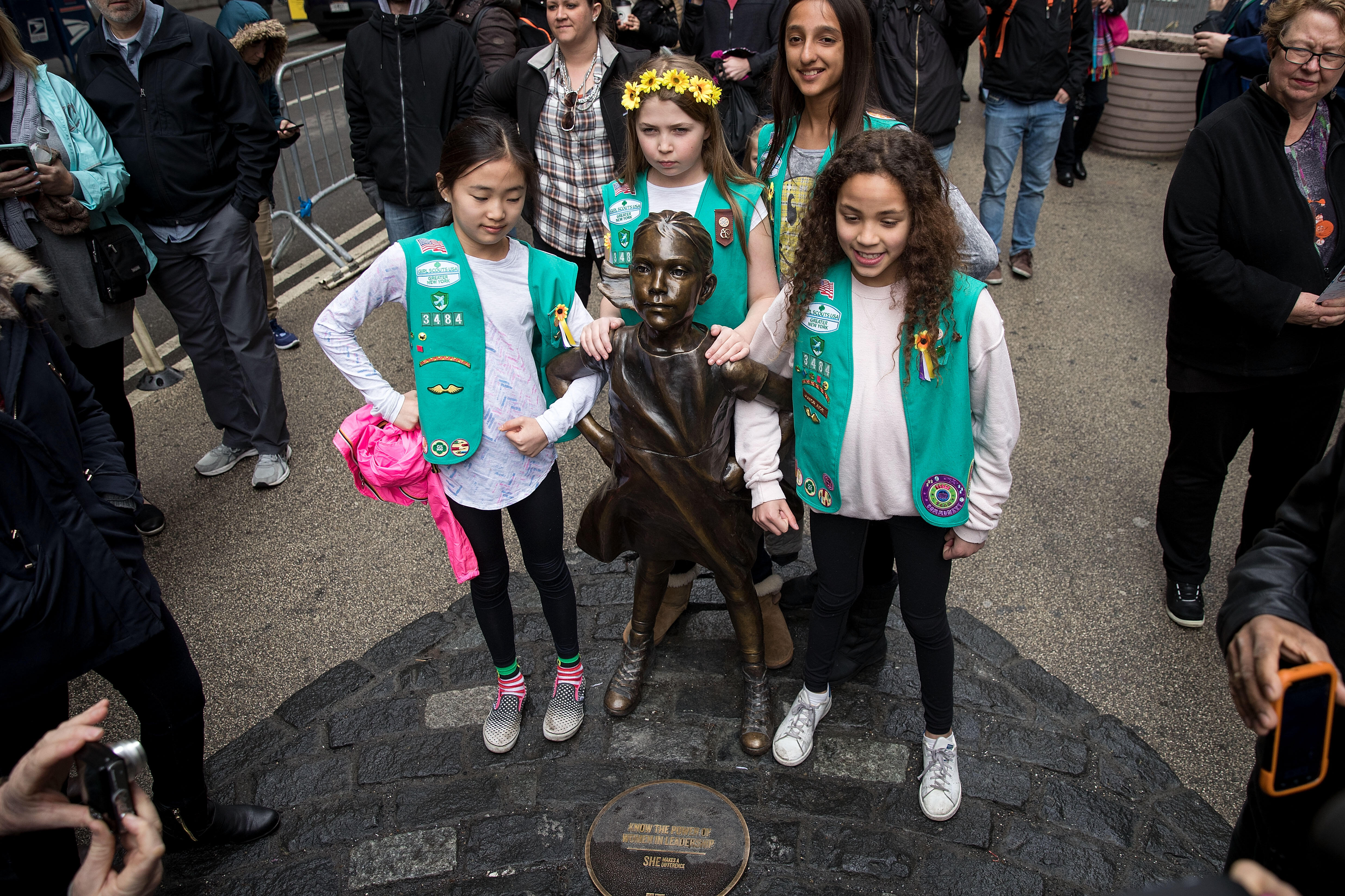 NEW YORK, NY - MARCH 27: Young members of Girl Scout troop 3484 pose for photos with the 'Fearless Girl' statue, March 27, 2017 in New York City. New York City Mayor Bill De Blasio announced that the popular statue of a young girl staring down the famous 