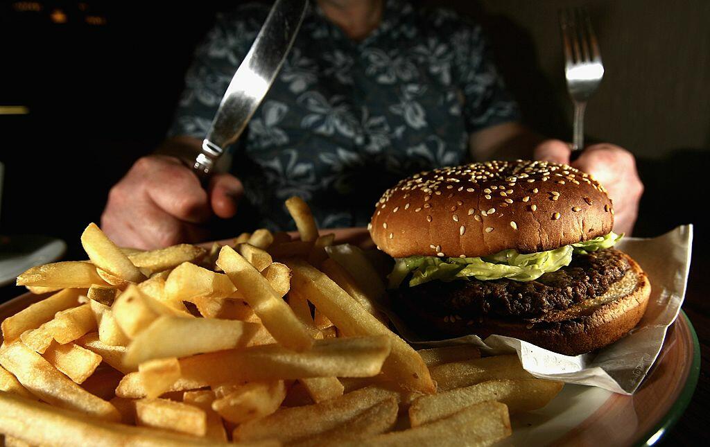 GLASGOW, UNITED KINGDOM - JUNE 07:  In this photo illustration a man eats a hamburger ind chips in a cafe on June 7,2006 in Glasgow, Scotland. New figures are suggesting that a large proportion of the population is clinically obese.  (Photo Illustration b
