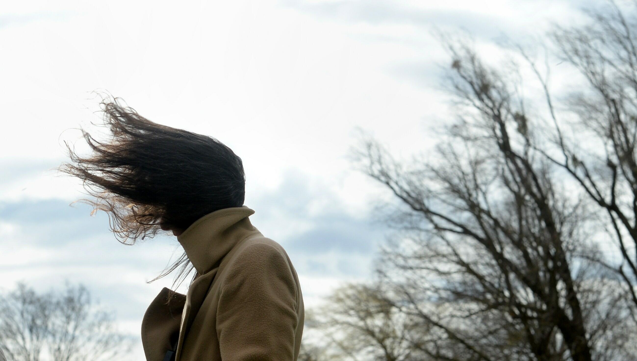 A woman has her hair fluttering in the wind during stormy weather near the lake Ammersee in the small Bavarian village of Herrsching, southern Germany, on March 31, 2015. Storm front 