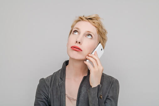 Portrait of blond woman with smartphone pouting mouth looking up