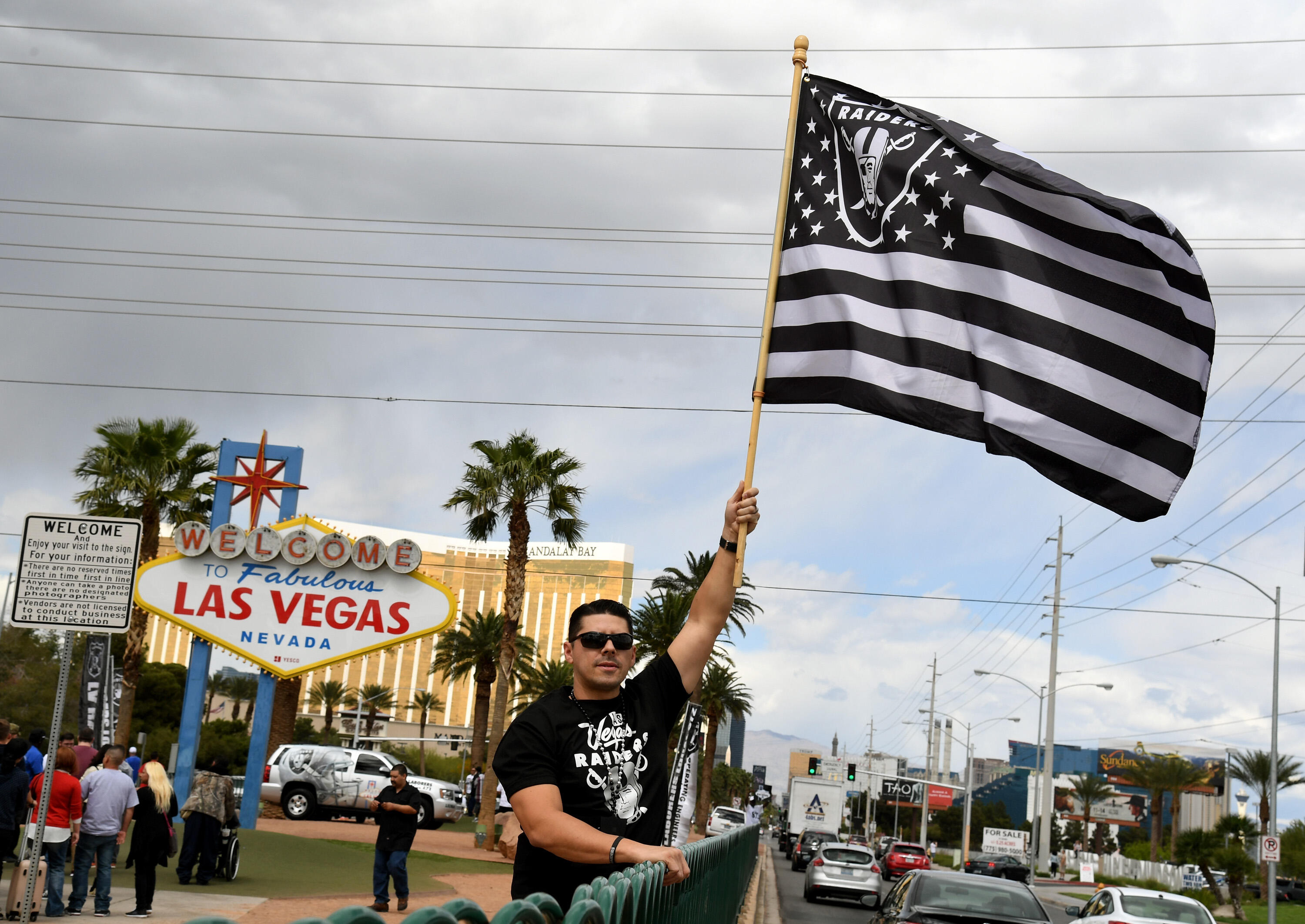LAS VEGAS, NV - MARCH 27:  Oakland Raiders fan Matt Gutierrez of Nevada waves a Raiders flag in front of the Welcome to Fabulous Las Vegas sign after National Football League owners voted 31-1 to approve the team's application to relocate to Las Vegas dur