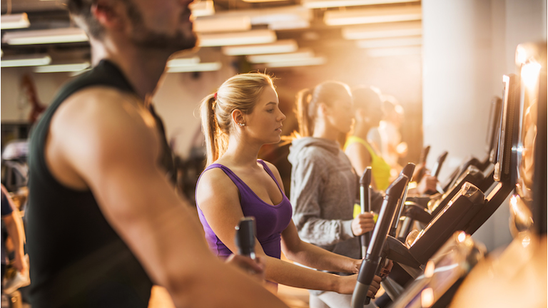 Group of people exercising on exercise machine in a gym.