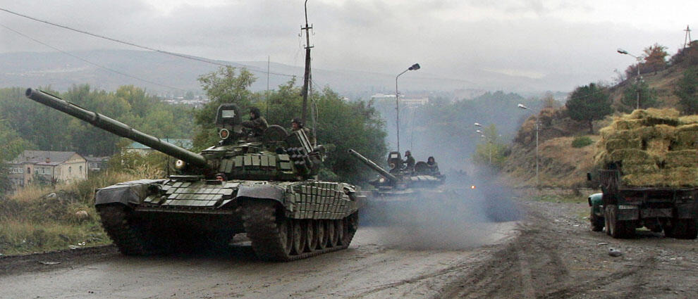 Russian tanks drive along a road outside