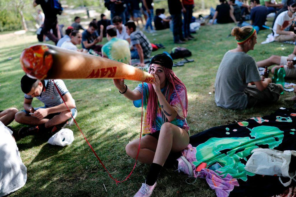An Israeli girl poses with a mock marijuana joint in Jerusalem on April 20, 2017 during a rally at the Rose garden, to celebrate 420 and to express their defiance of current laws. Sitting in small groups on mats shaded by trees in the Rose Garden just across from the Knesset, participants lit up as the clock struck 4:20 for the local version of the traditional worldwide April 20 pro-marijuana events, known as 