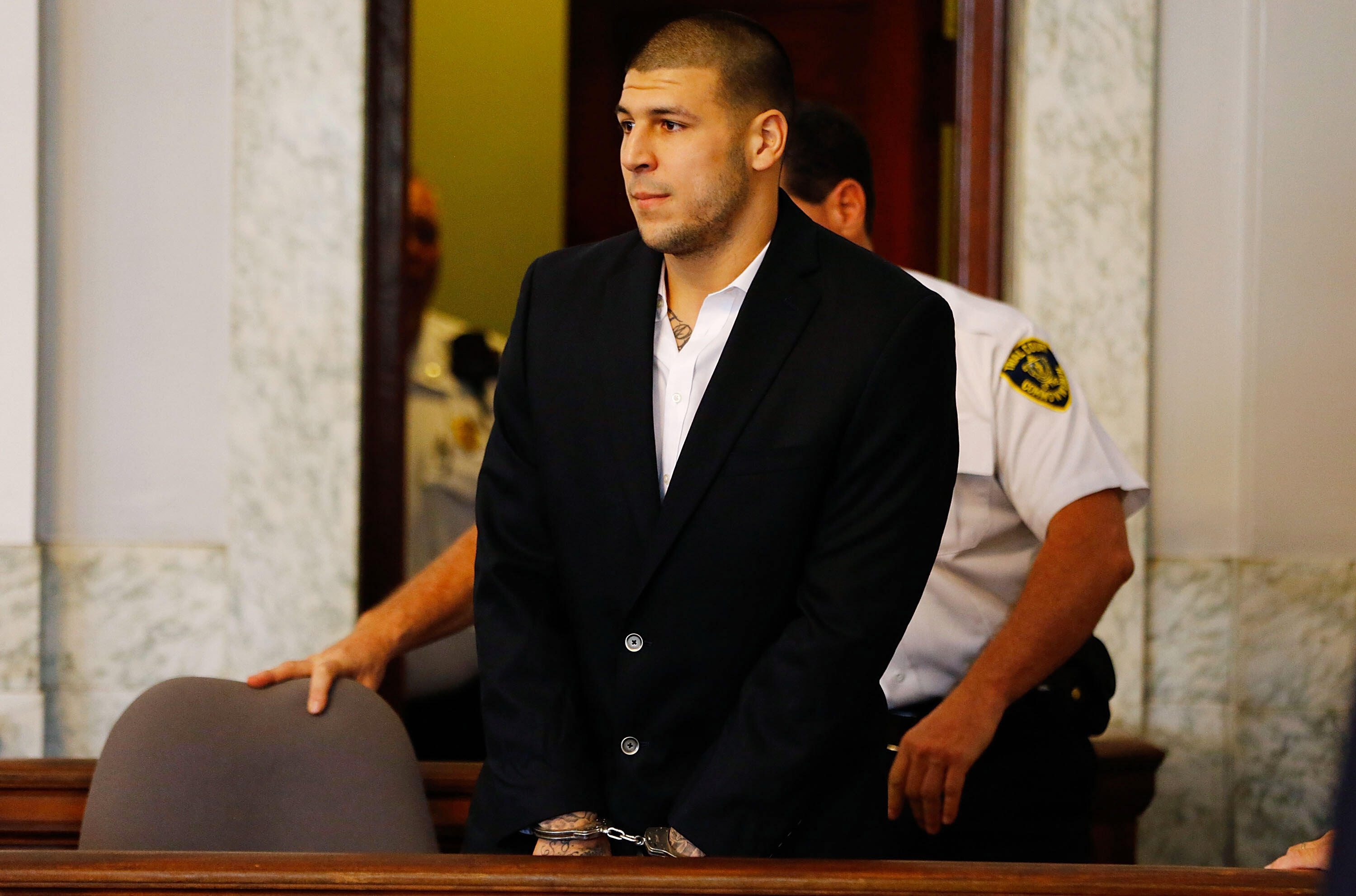 NORTH ATTLEBORO, MA - AUGUST 22: Aaron Hernandez is escorted into the courtroom of the Attleboro District Court for his hearing on August 22, 2013 in North Attleboro, Massachusetts. Former New England Patriot Aaron Hernandez has been indicted on a first-d